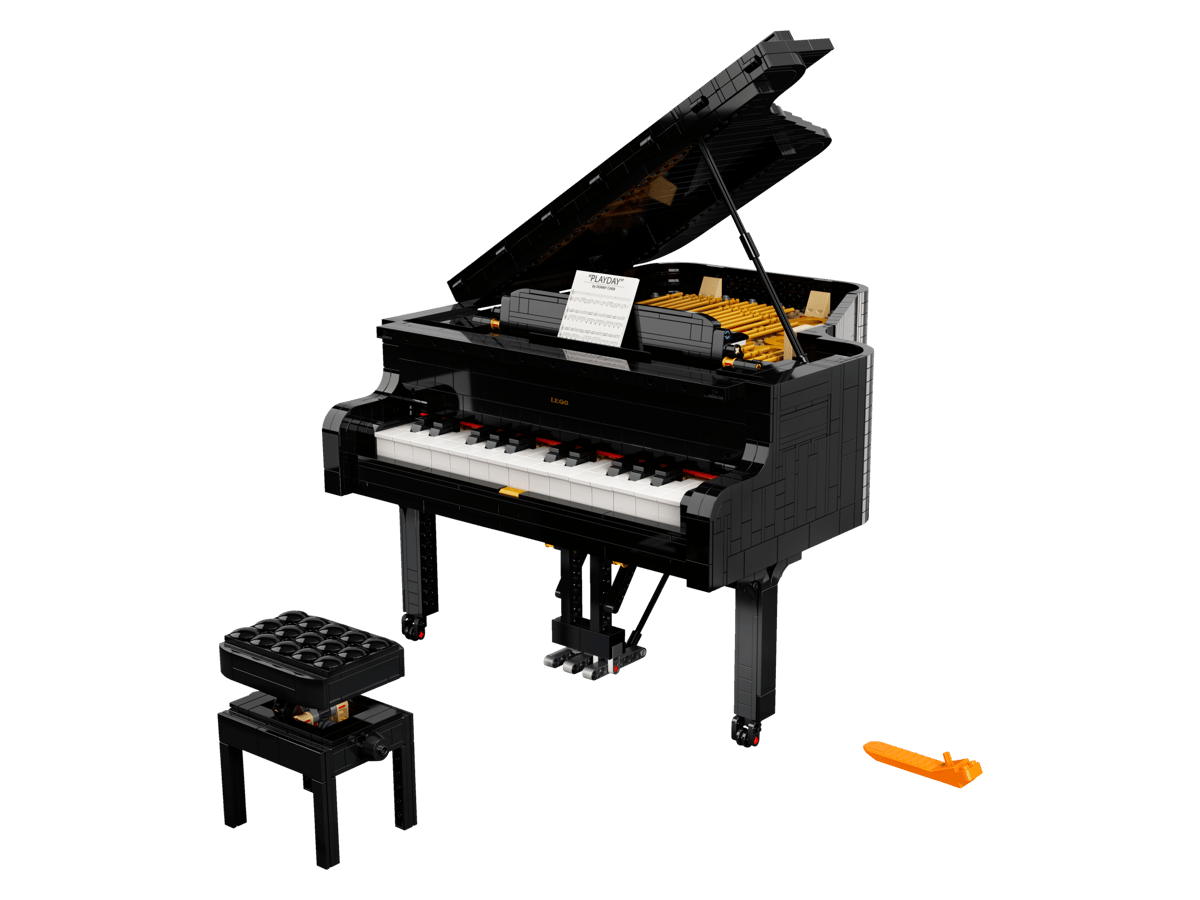 LEGO Grand Piano Ideas model built in polished sleek black with the top lid propped open showing the internal golden strings and a small sheet music stand on the keys