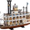 A massive multi deck historic riverboat representing the River Steamboat LEGO set featuring detailed white railings black smokestacks and a large red paddle wheel at the back