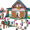 The official retail packaging box showing the completed Horse Stable LEGO forest riding center building with textured wood siding blue roofs a gray horse and a tan horse being ridden by mini dolls near a campfire