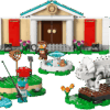 The completed Blathers Museum LEGO building showing the tan facade with a green roof owl crest medallion and twin white pillars standing behind an outdoor fountain a triceratops fossil skeleton and a frog villager minifigure fishing